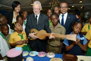Minister of Education Ronald Thwaites strums a hand-made guitar with students at a First Global "Perfect Pitch" event.