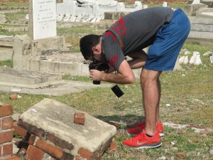 A Jewish volunteer with Jamaican heritage photographs a child's gravestone.
